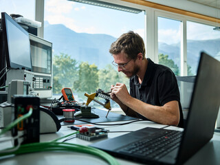 Male engineer soldering electrical component at factory