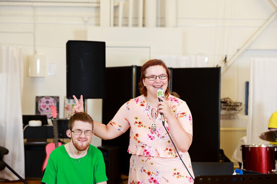 Woman holding microphone and giving man bunny ears