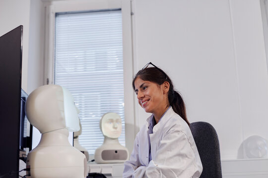 Smiling female engineer looking at robot