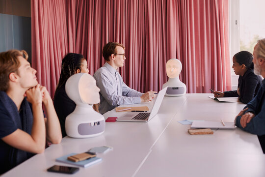 Business people discussing robot voice assistant during meeting