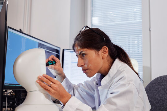 Female engineer building robot at work station