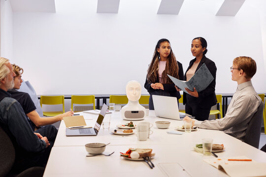Business people discussing robot voice assistant during meeting