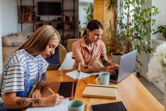 A female couple sitting at their kitchen table together while working from home