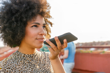Afro young woman talking on smart phone at terrace