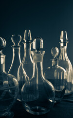 Vintage background. Antique bottles of different types against the dark wall. Monochrome vertical image.
