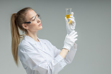 Chemical test tubes and flasks with petroleum products, the girl is a laboratory assistant, safety glasses