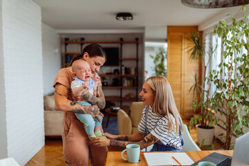 Multitasking Mothers. Lesbians playing with their baby at home