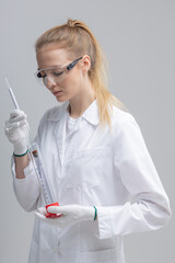 Chemical test tubes and flasks with petroleum products, the girl is a laboratory assistant, safety glasses. white gloves. measuring cylinder, hydrometer