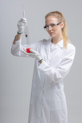 Chemical test tubes and flasks with petroleum products, the girl is a laboratory assistant, safety glasses. white gloves. measuring cylinder, hydrometer