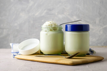 cans of homemade yogurt and spoons on a cutting board next to a kitchen towel