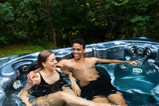 Smiling young couple sitting in jacuzzi