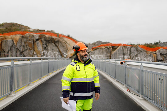 Male engineer in reflecting clothing standing on bridge