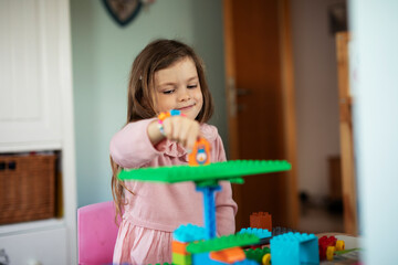 Adorable girl playing with toys at home. Little child playing with lots of toys indoor