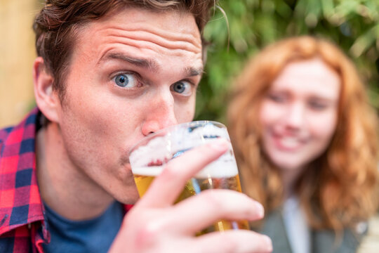 Man with raised eyebrows drinking beer at pub