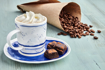 Cup of coffee with whipped cream, broken chocolate