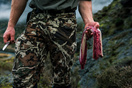 Mid section of hunter holding raw meat