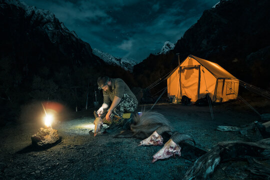 Hunter preparing mountain goat's skulls in evening