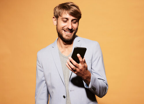 Smiling Man With Blond Hair Looking At Mobile Phone