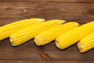 Sweet yellow corn lies on a wooden table.