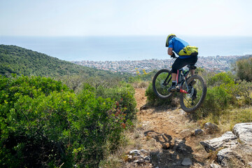 Male cyclist in mid-air with electric mountain bike during sunny day