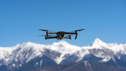 Drone hovering on the background of snow capped mountains. Sochi, Russia.