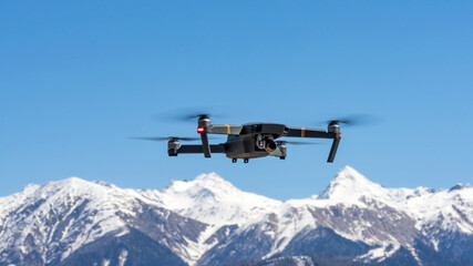 Fototapeta na wymiar Drone hovering on the background of snow capped mountains. Sochi, Russia.