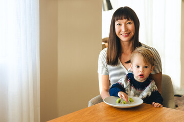 Fototapeta premium Happy Mother With Son Having Kiwi Fruit At Home