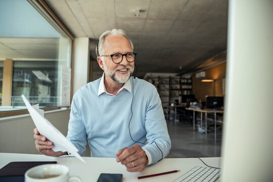 Smiling male entrepreneur doing video call on computer at office