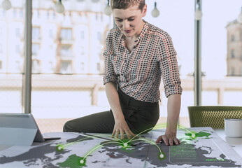 Female professional looking at communication data on map at desk in office