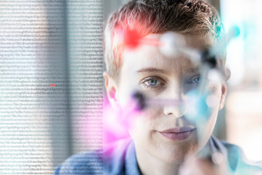 Female professional behind molecular structure at office