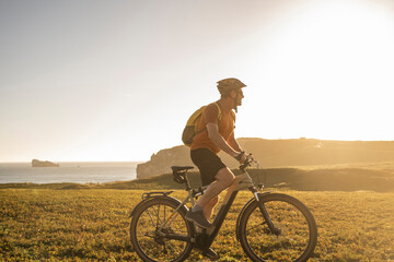Male athlete riding electric mountain bike on grass