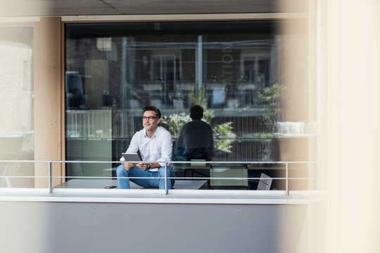 Businessman with digital tablet sitting at office balcony