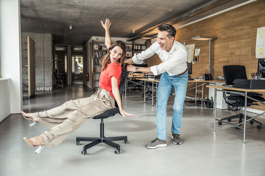 Male and female colleague having fun while playing in office - Powered by Adobe