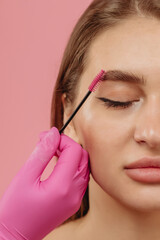 girl combs her eyebrow with a brush
