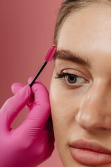 girl combs her eyebrow with a brush
