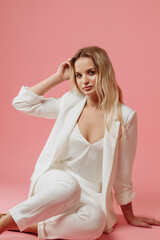beautiful girl in a white suit on a pink background
