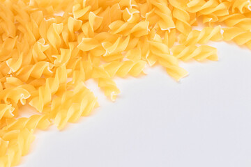 Uncooked Fusilli Pasta with Copy Space on White Background. Raw and Dry Macaroni. Fat and Unhealthy Food - Flat Lay