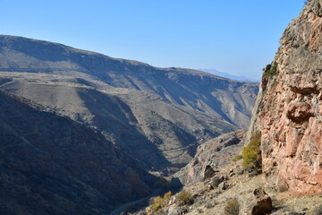 Panoramic view of the mountains on a sunny day. View of sheer cliffs and a stream in the gorge.