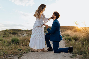 Man on one knee proposing girlfriend during sunset