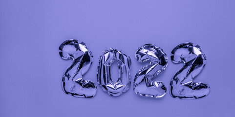 Foil balloons in form of numbers 2022 on lavender color background