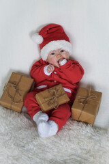 happy newborn baby in santa claus outfit with eco friendly natural paper gift box for christmas lying on white background
