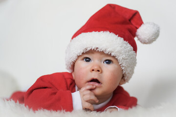 happy newborn baby in santa claus outfit with eco friendly natural paper gift box for christmas lying on white background

