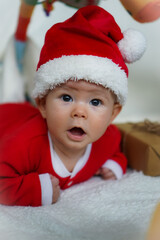 happy newborn baby in santa claus outfit making wow expression with eco friendly natural paper gift box for xmas