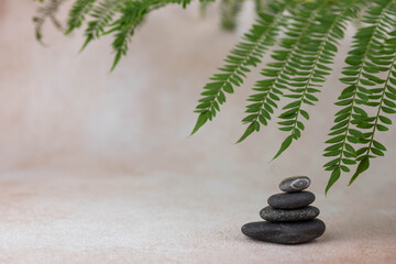 Pyramids of gray zen pebble meditation stones with green leaves on beige background. Concept of harmony, balance and meditation, spa, massage, relax.