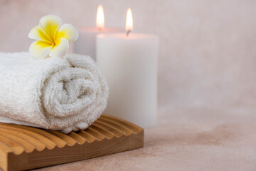 Plakat Spa still life treatment composition on massage table in wellness center. Twisted hot towel with aromatic candles on beige background. Aroma therapy setting. Concept of harmony, balance and meditation