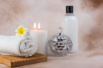 Obraz na płótnie Canvas Spa still life treatment composition on massage table in wellness center. Twisted hot towel with aromatic candles on beige background. Aroma therapy setting. Concept of harmony, balance and meditation