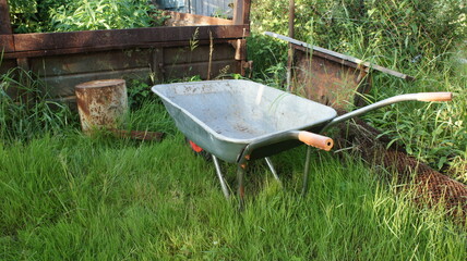 Garden wheelbarrow on green grass, rustic landscape