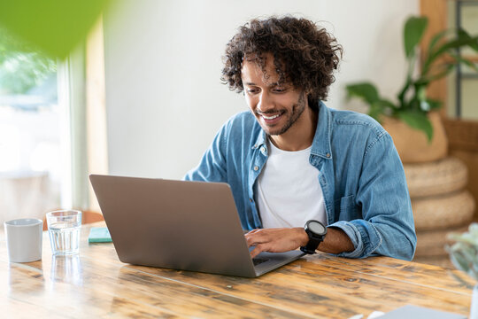 Cheerful male entrepreneur working on laptop at home