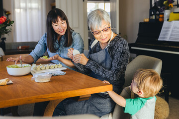 Boy Looking At Family Preparing Dumplings At Home