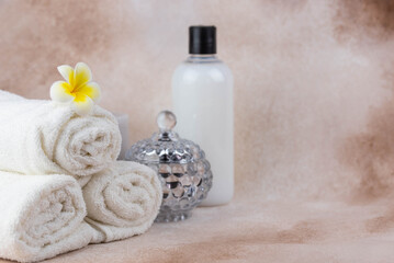 Spa still life treatment composition on massage table in wellness center. Twisted hot towel with aromatic candles on beige background. Aroma therapy setting. Concept of harmony, balance and meditation